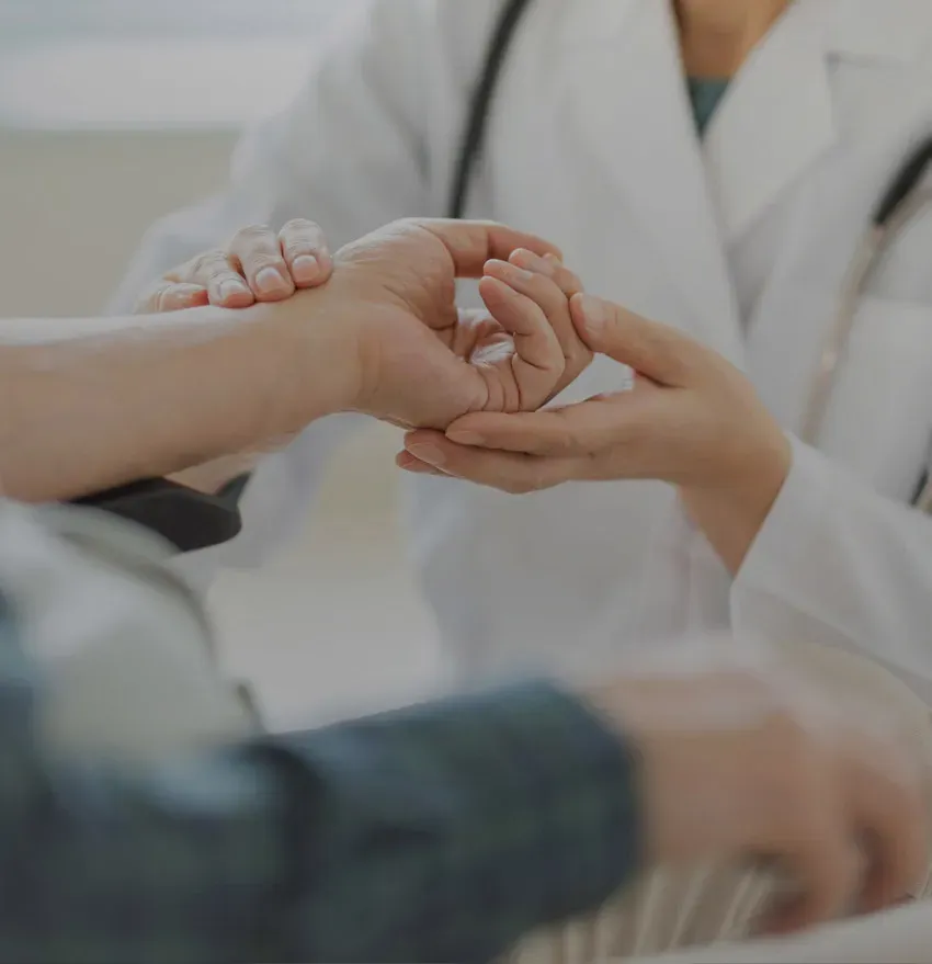 A doctor in a white coat checks a patients pulse by gently holding their wrist, conveying a sense of care and medical examination.