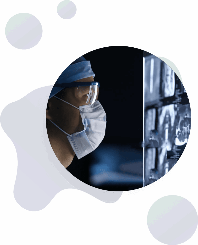 A person wearing a surgical mask, cap, and protective glasses closely examines medical scans displayed on a screen in a dark room. Abstract shapes decorate the background.