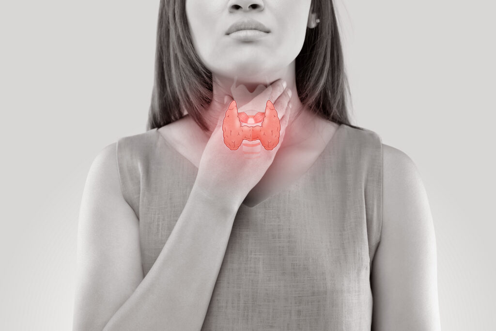 A woman touches her throat, with an illustrated image of the thyroid gland highlighted in red over her neck, suggesting issues or pain in the thyroid area.