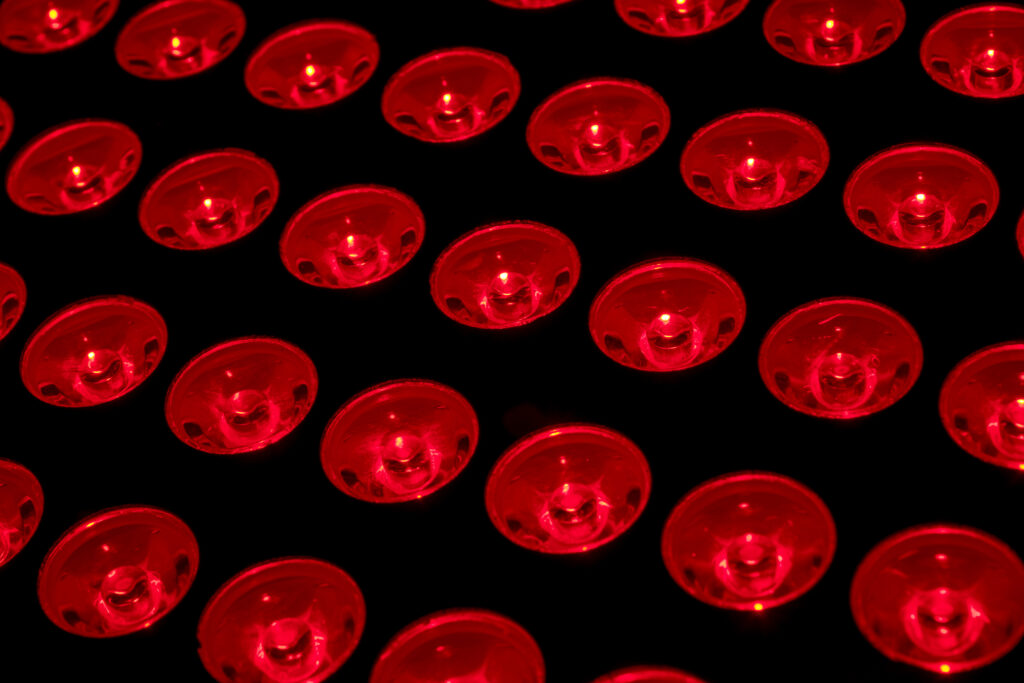 Rows of circular red LED lights glowing brightly on a black background, creating a repeating geometric pattern.