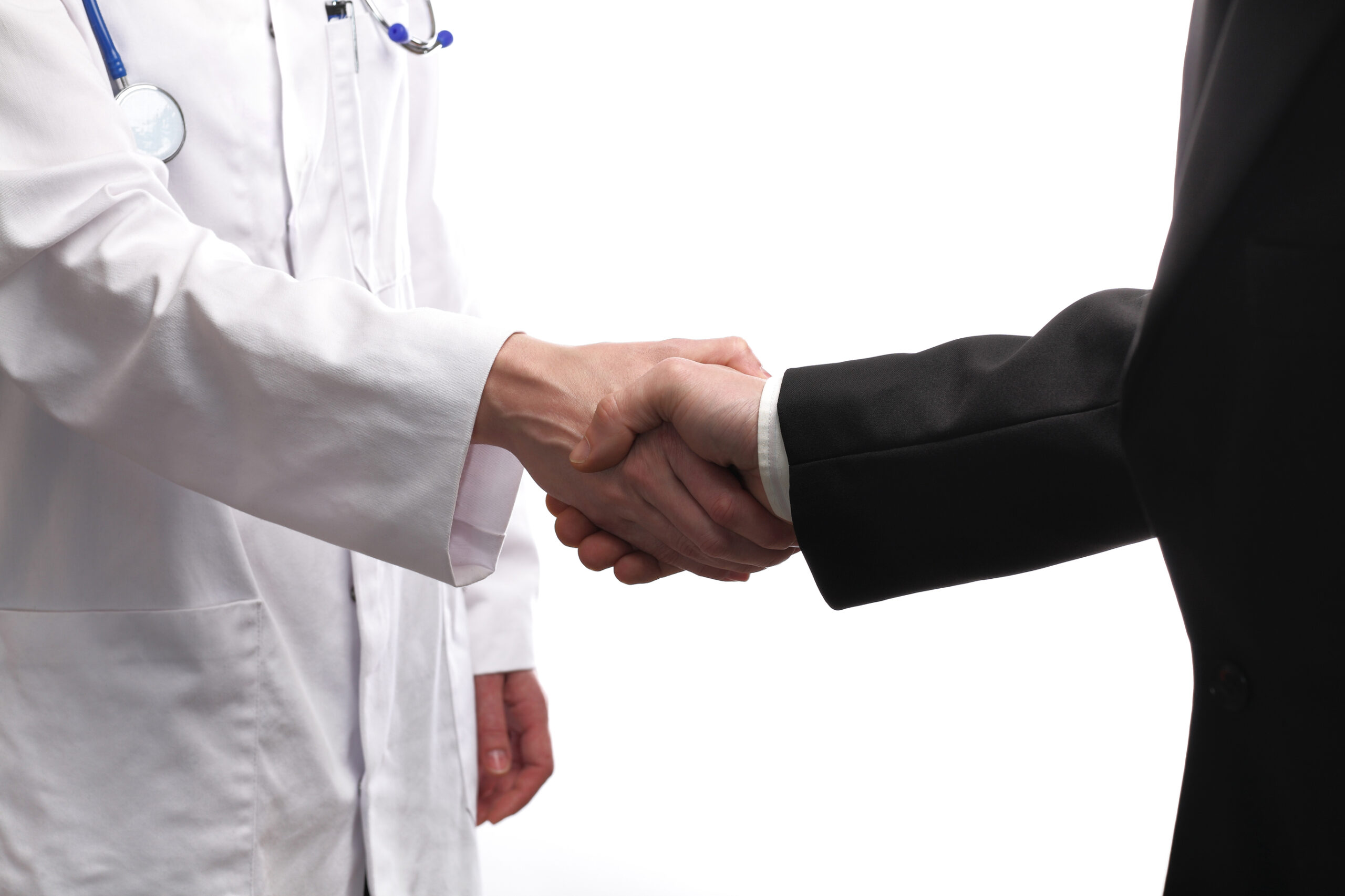 A doctor in a white coat with a stethoscope shakes hands with a person in a black suit, symbolizing partnership or agreement, against a plain white background.