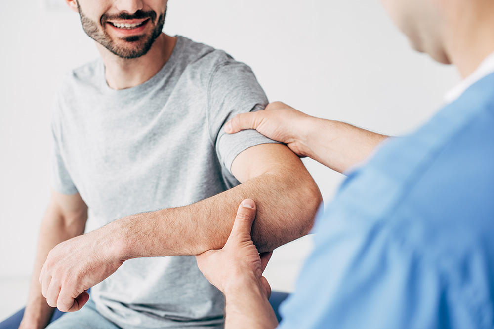 Selective focus of smiling patient sitting on couch and medical practitioner examining the patient.