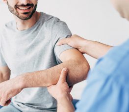 Selective focus of smiling patient sitting on couch and medical practitioner examining the patient.