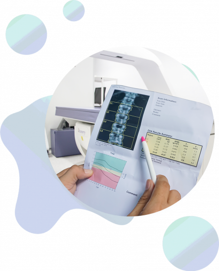 Person holding a photo of DEXA densitometry spine scan with a DEXA machine in the background.